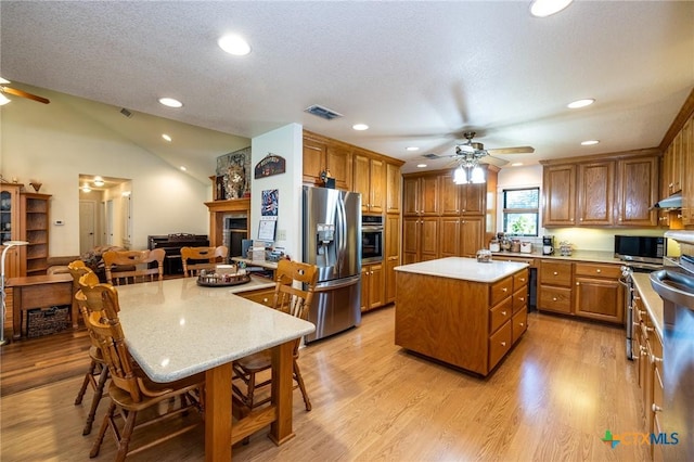 6589 State Highway 304, Harwood, TX 78632 - kitchen featuring a ceiling fan, stainless steel appliances, a kitchen island, brown cabinetry, and a breakfast bar