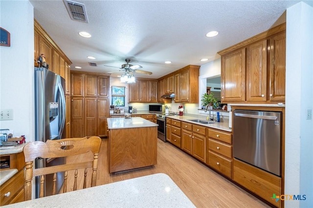 6589 State Highway 304, Harwood, TX 78632 - kitchen featuring appliances with stainless steel finishes, a sink, light wood finished floors, brown cabinetry, and under cabinet range hood