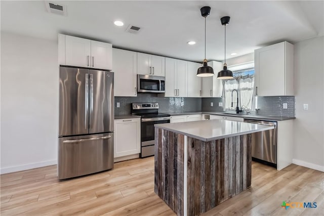 kitchen with sink, stainless steel appliances, white cabinets, and a kitchen island