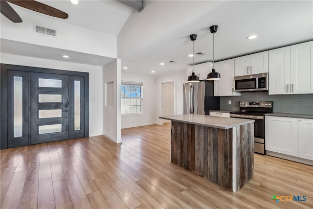 kitchen with white cabinetry, a center island, hanging light fixtures, appliances with stainless steel finishes, and backsplash