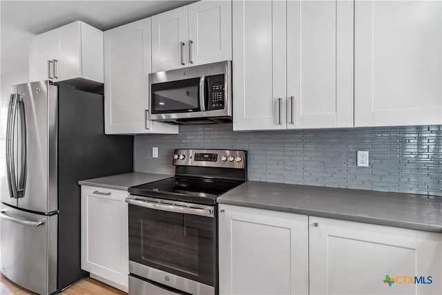 kitchen featuring tasteful backsplash, white cabinets, and appliances with stainless steel finishes