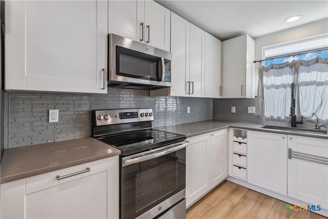 kitchen featuring white cabinetry, stainless steel appliances, sink, and backsplash