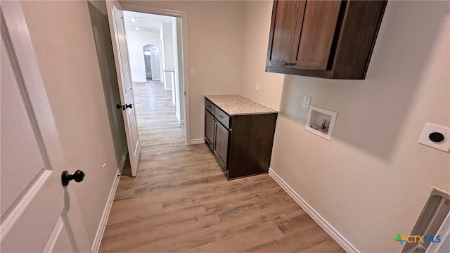 clothes washing area with washer hookup, arched walkways, hookup for an electric dryer, light wood-style floors, and cabinet space