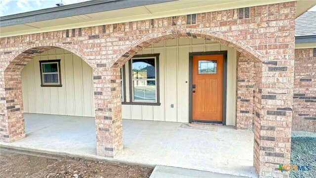 entrance to property featuring brick siding and board and batten siding
