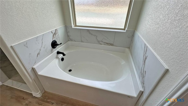 full bath with a textured wall and a garden tub
