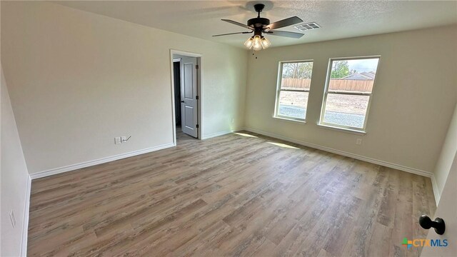 unfurnished room featuring a textured ceiling, visible vents, baseboards, ceiling fan, and wood finished floors