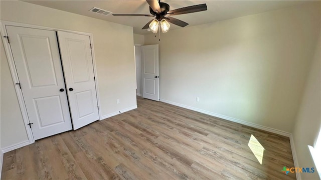 unfurnished bedroom featuring a closet, a ceiling fan, wood finished floors, baseboards, and visible vents