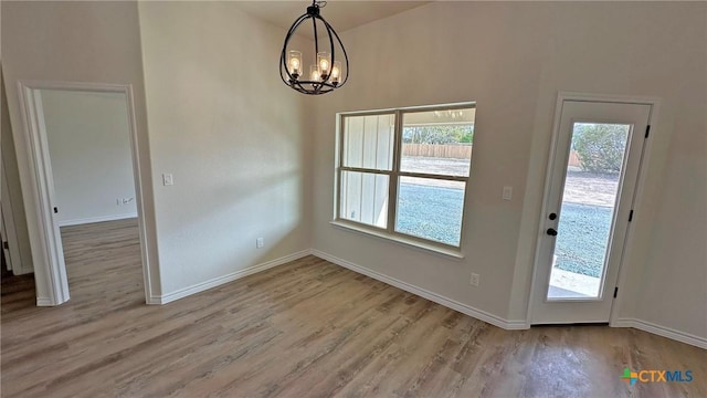 unfurnished dining area with light wood-style floors, a healthy amount of sunlight, and a chandelier