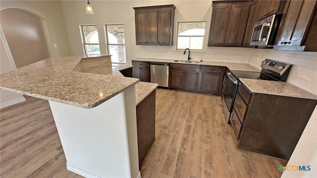 kitchen with tasteful backsplash, light wood-style floors, a sink, and stainless steel appliances