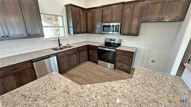 kitchen with tasteful backsplash, light stone counters, a sink, and stainless steel appliances