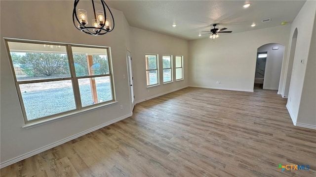 interior space featuring vaulted ceiling, ceiling fan with notable chandelier, baseboards, arched walkways, and wood finished floors