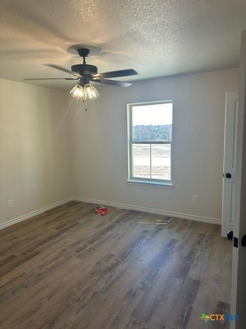 spare room with ceiling fan, dark hardwood / wood-style floors, and a textured ceiling