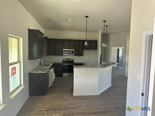 kitchen with a center island, appliances with stainless steel finishes, sink, pendant lighting, and dark hardwood / wood-style flooring