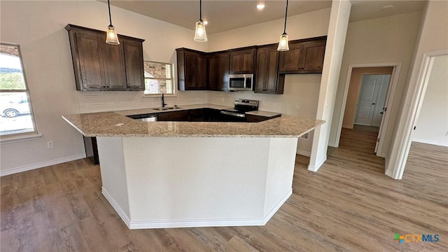 kitchen featuring a sink, dark brown cabinets, appliances with stainless steel finishes, and light stone counters