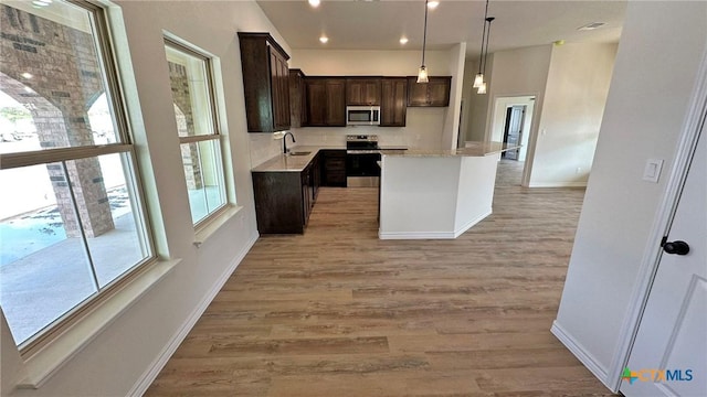 kitchen with light countertops, dark brown cabinetry, a sink, light wood finished floors, and stainless steel appliances