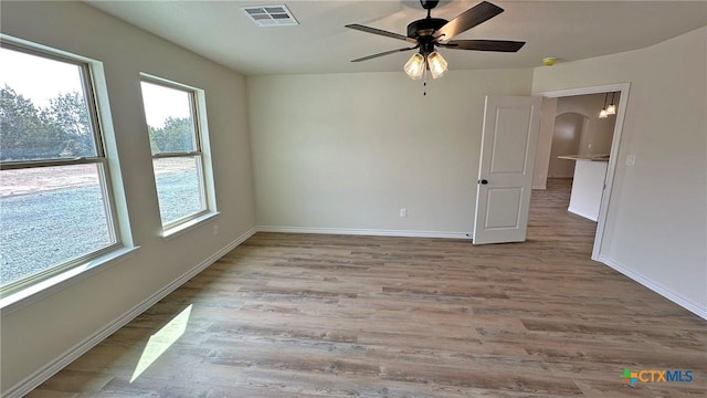 unfurnished room featuring a ceiling fan, wood finished floors, baseboards, and visible vents