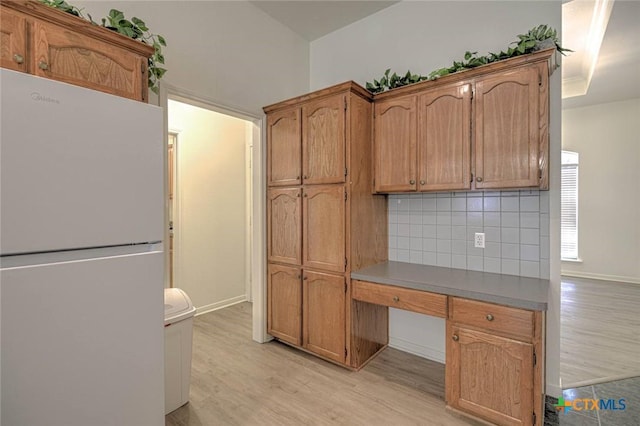 2109 Southport Dr, Killeen, TX 76542 - kitchen with freestanding refrigerator, light wood-style flooring, backsplash, a desk, and brown cabinetry