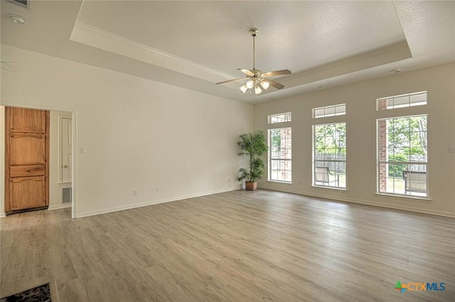 2109 Southport Dr, Killeen, TX 76542 - unfurnished room featuring a raised ceiling, light wood-style floors, a ceiling fan, and healthy amount of natural light