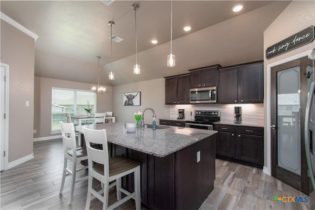 503 Willow Dr, Troy, TX 76579 - kitchen featuring stainless steel appliances, vaulted ceiling, light stone countertops, decorative backsplash, and light wood-type flooring