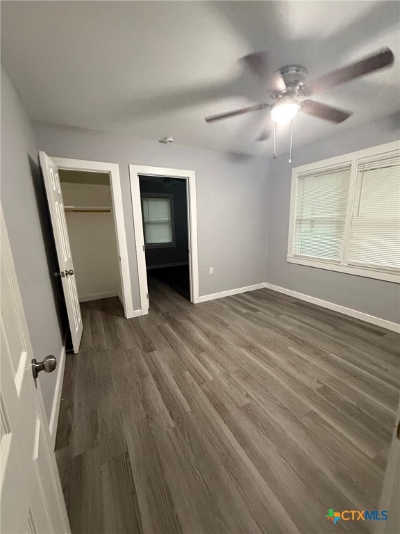 1803 E Leon St, Gatesville, TX 76528 - unfurnished bedroom with dark wood finished floors, baseboards, two closets, and a ceiling fan