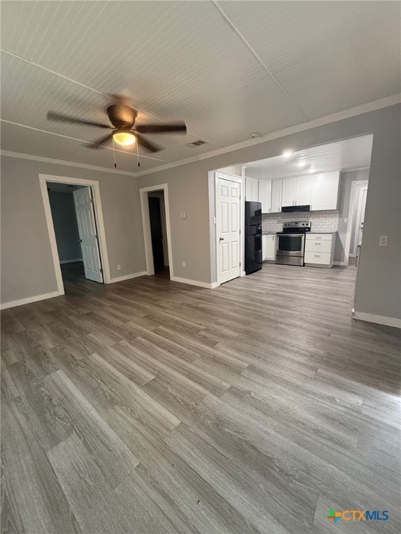 1803 E Leon St, Gatesville, TX 76528 - unfurnished living room with baseboards, crown molding, wood finished floors, and a ceiling fan