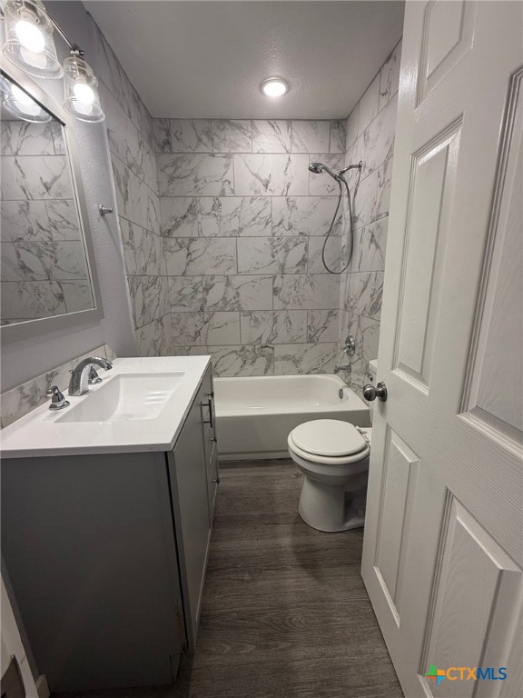 1803 E Leon St, Gatesville, TX 76528 - bathroom with toilet, vanity, wood finished floors, and tub / shower combination