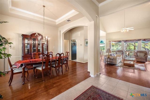 tiled dining room with a towering ceiling, ceiling fan with notable chandelier, and ornamental molding