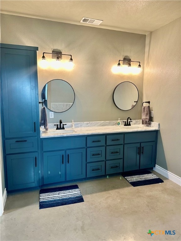 bathroom with concrete flooring, vanity, and a textured ceiling