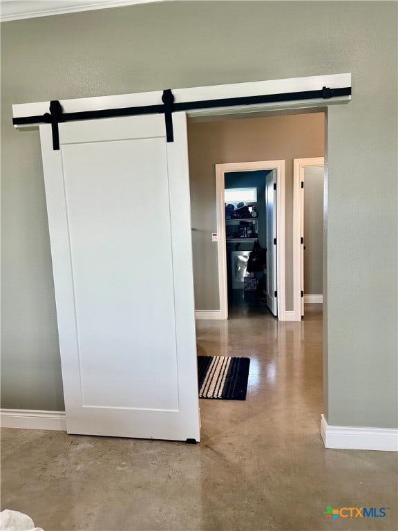 hallway with a barn door and concrete flooring