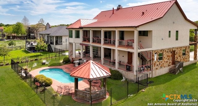 back of house with a fenced in pool, a lawn, a patio, and a balcony