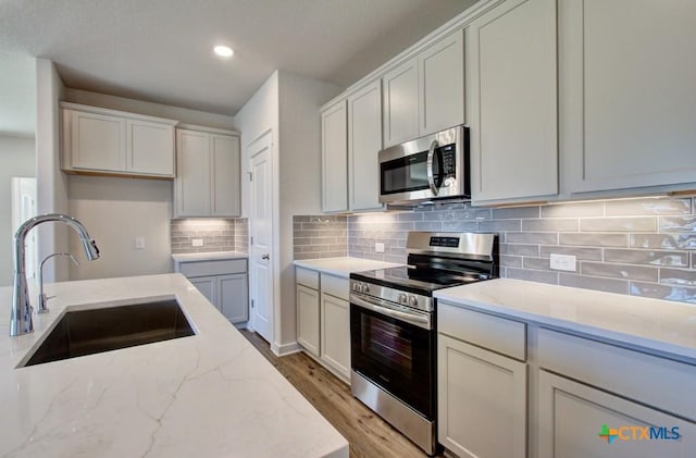911 Cloud Sky Rd, New Braunfels, TX 78130 - kitchen featuring stainless steel appliances, light wood-type flooring, light stone countertops, backsplash, and recessed lighting