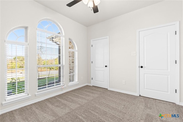 carpeted spare room with ceiling fan and plenty of natural light