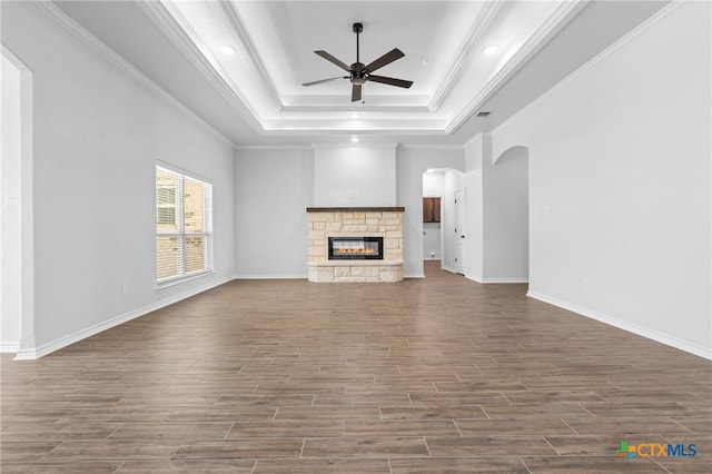 unfurnished living room featuring ceiling fan, ornamental molding, a fireplace, and a tray ceiling