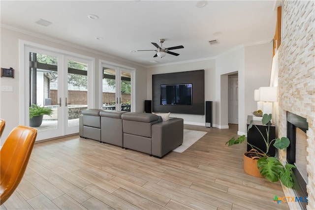 3836 Newland Ct, Round Rock, TX 78681 - living area featuring french doors, a ceiling fan, light wood-style floors, crown molding, and a stone fireplace