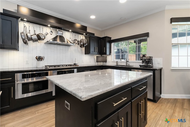 3836 Newland Ct, Round Rock, TX 78681 - kitchen with appliances with stainless steel finishes, a sink, dark cabinets, wall chimney exhaust hood, and tasteful backsplash