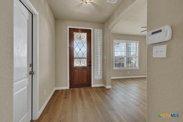 entryway with visible vents, wood finished floors, baseboards, and a textured wall