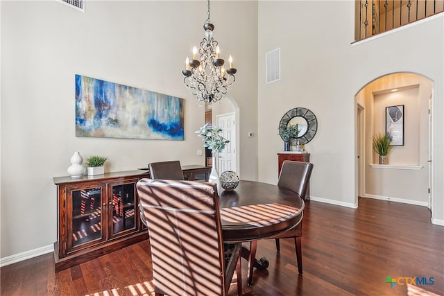 dining area with a high ceiling, dark hardwood / wood-style floors, and an inviting chandelier