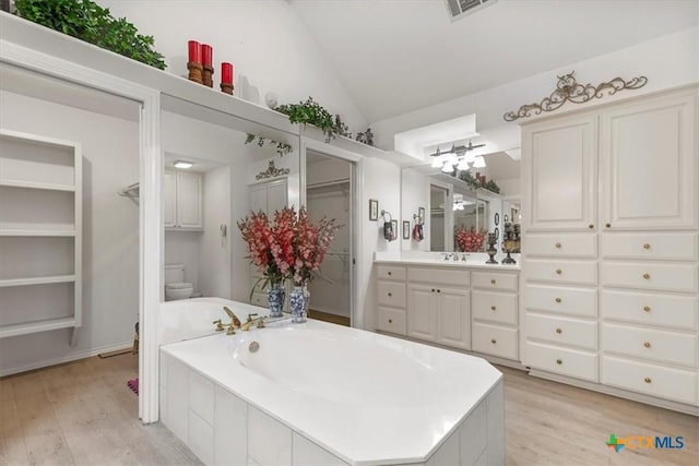 2113 Highland Dr, Salado, TX 76571 - bathroom with lofted ceiling, wood finished floors, toilet, a garden tub, and vanity
