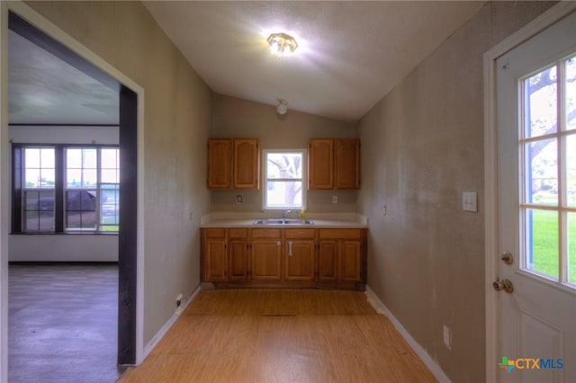 kitchen with sink, lofted ceiling, and light wood-type flooring