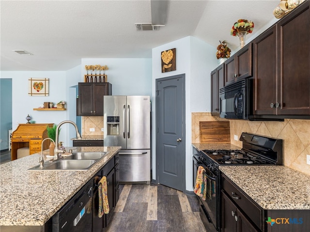 900 Hatton Hill Ln, Austin, TX 78725 - kitchen featuring black appliances, dark wood finished floors, dark brown cabinets, a kitchen island with sink, and backsplash