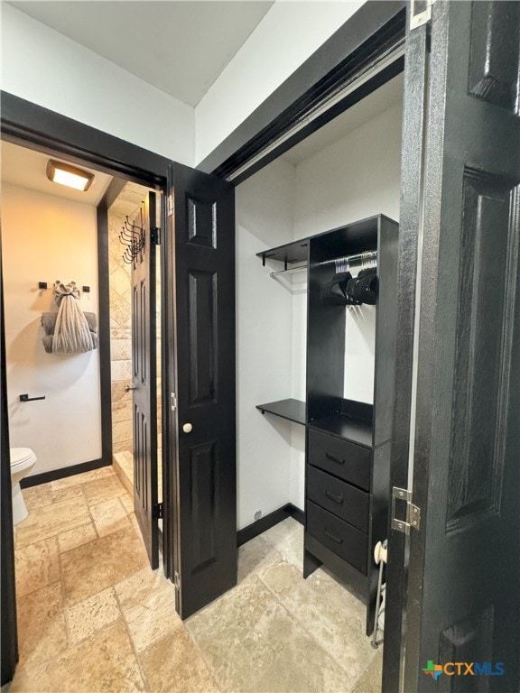 walk in closet featuring stone tile floors