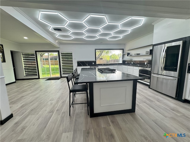 kitchen featuring dark countertops, appliances with stainless steel finishes, a center island, and light wood-type flooring