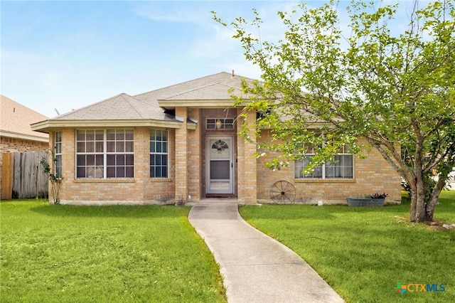 view of front of house featuring brick siding, a front lawn, and fence
