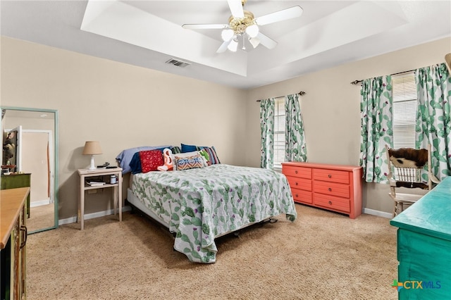 bedroom with a tray ceiling, carpet floors, a ceiling fan, and baseboards