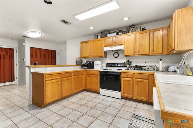 kitchen with under cabinet range hood, light countertops, electric stove, a sink, and a peninsula