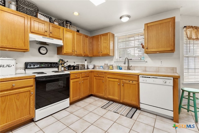 kitchen featuring white dishwasher, a sink, tile countertops, range with electric cooktop, and under cabinet range hood