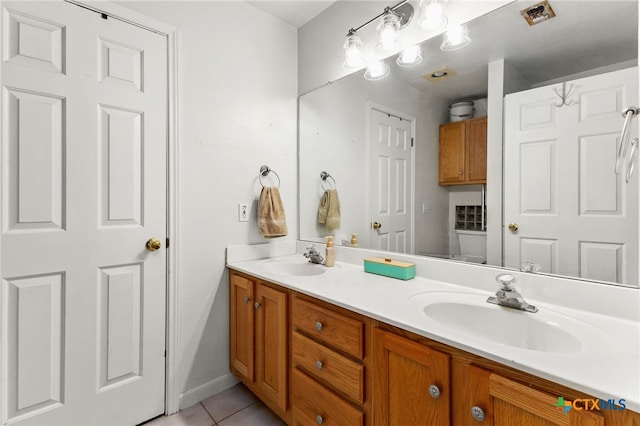 bathroom featuring tile patterned floors, baseboards, a sink, and double vanity