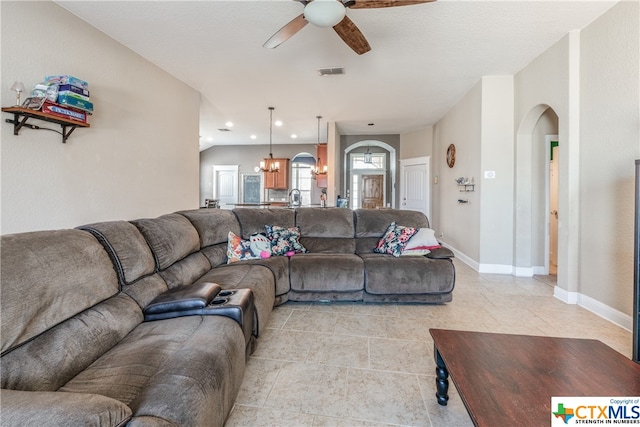 tiled living room with ceiling fan with notable chandelier