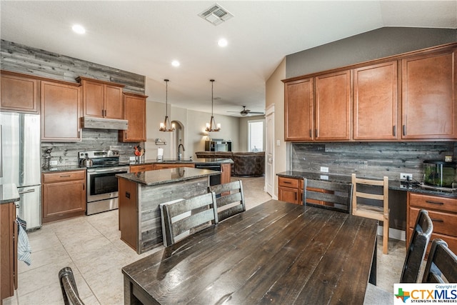 kitchen featuring ceiling fan with notable chandelier, lofted ceiling, decorative backsplash, appliances with stainless steel finishes, and decorative light fixtures