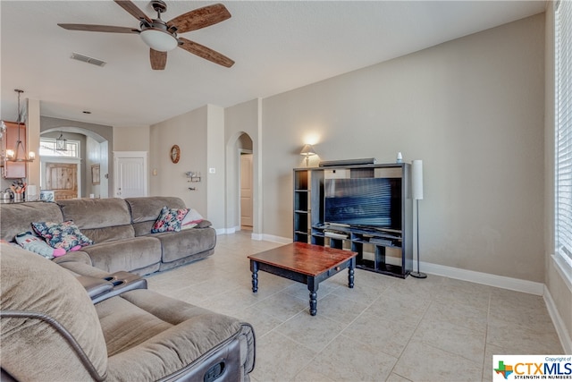 tiled living room featuring ceiling fan with notable chandelier